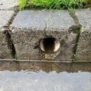 Underground rain gutter output exiting the sidewalk curb
